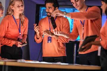 A diverse team of young innovators in a tech lab presents a new smartphone prototype,...