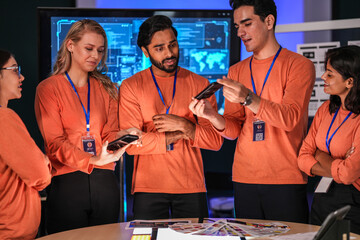 A diverse team of young innovators in a tech lab presents a new smartphone prototype,...