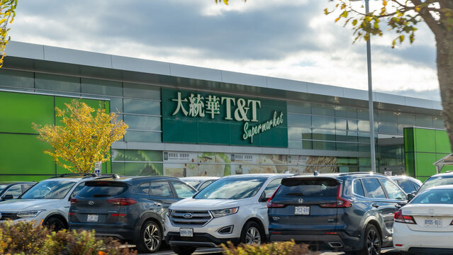 T and T Supermarket storefront with green signage, surrounded by parked cars and autumn trees, showcasing a vibrant shopping environment with copy space