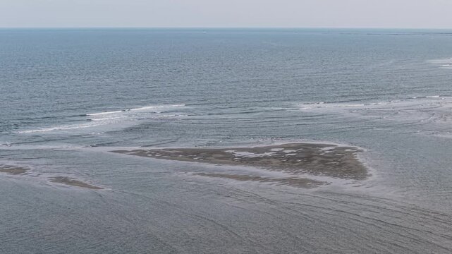 Aerial view of a small tidal island surrounded by ocean waves off the coast of South Carolina