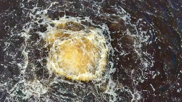 high-angle explosion, mid-air shot of an explosive, amber-colored upwelling of water stirring the dark, churning Baltic Sea on a stormy summer day, suggesting a submerged mysterious event