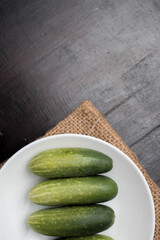 Flat lay of cucumber on a plate on a dark wooden background with clear space area so it is perfect for background content