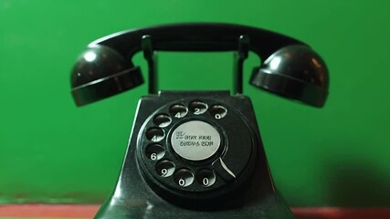 A vintage rotary phone against a green background, evoking nostalgia.