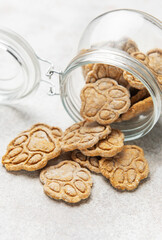 Homemade paw print dog treats spilling from jar