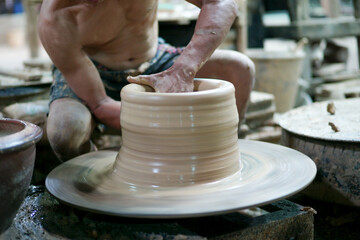 Selective focus on the clay work on the spinning tray with hands of worker