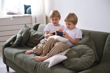 kids boys twins using smartphones on the couch in living room