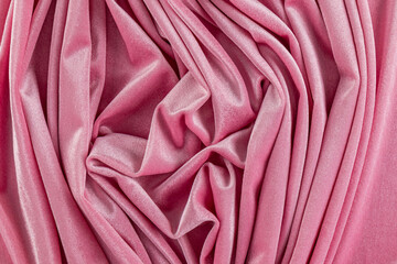 beautiful frequent folds of velvet fabric of delicate pink color. Beautiful abstract pattern of pink velvet folds. drapery