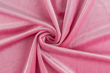Chic velvet fabric in pink delicate color twisted in a spiral. elegant folds of soft velvet. layout for design, advertising of the product. top view