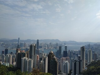 Naklejka premium Panoramic view of Hong Kong skyline and Victoria Harbour from The Peak on a sunny day