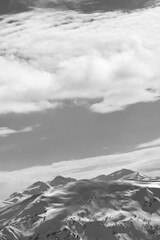 Fototapeta premium Snowy mountains and sunlight sky with clouds at winter evening