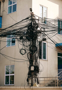 Urban utility pole with tangled wires in a city setting near buildings