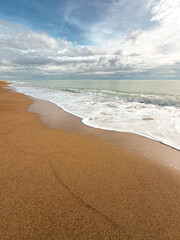 Gentle sea waves touching sandy beach under dramatic cloudy sky
