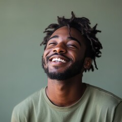 Obraz premium Joyful smiling man portrait, candid lifestyle headshot with dreadlocks and beard, natural light on green background