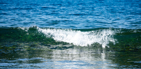 Sea waves creating white foam. Bright sunlight reflects on ocean waves in motion. Wave texture.