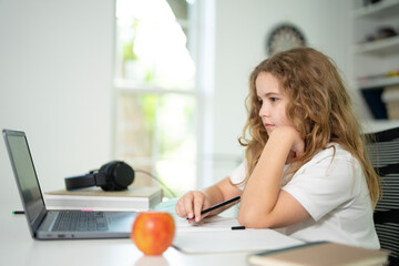 Kid using laptop for online studying at home. Child sitting at desk on virtual school lesson. Teenager learning with notebook and computer. Young student. Kids remote online class.