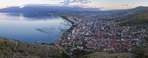 Blue hour aerial view of Pogradec, Albania, showing the city spreading along Lake Ohrid with calm reflections and surrounding mountains.