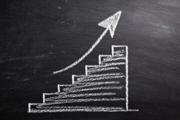 A chalk drawing on a dark surface shows a staircase with an upward-pointing arrow. The style evokes progress and upward movement