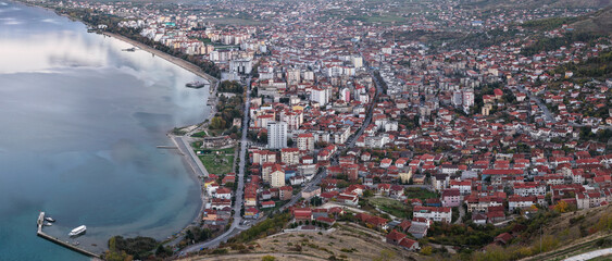 Aerial view of Pogradec, Albania, showcasing the dense urban layout along the shoreline of Lake Ohrid during calm evening light.