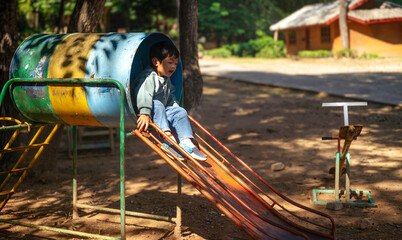 Asian Little Boy Sliding on Playground Equipment Outdoors, Happy Child Enjoying Playtime