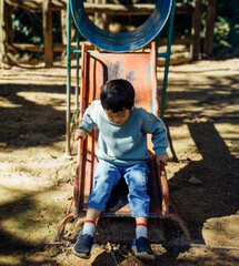 Asian Little Boy Sliding on Playground Equipment Outdoors, Happy Child Enjoying Playtime