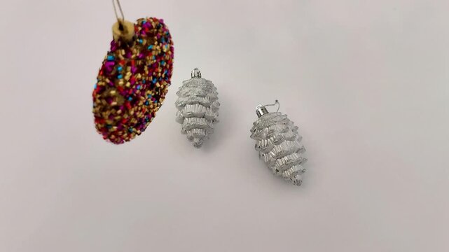 Glittered ornaments and silver pinecones rest on a table as soft light highlights their textures, creating a simple, festive holiday setup with calm seasonal detail