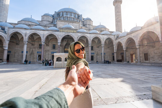 Woman holding hand exploring grand mosque courtyard in Istambul, Turkey