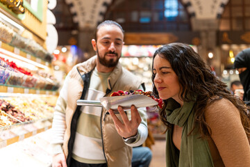 Tourist smelling dried fruits in Istanbul spice market bazaar