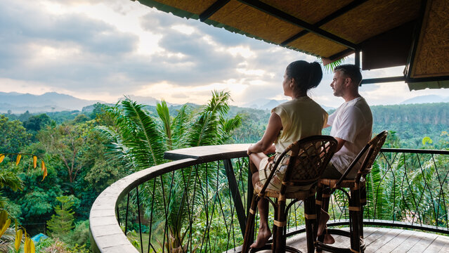 Romantic couple enjoying sunrise views from balcony in Khao Sok National Park, Thailand