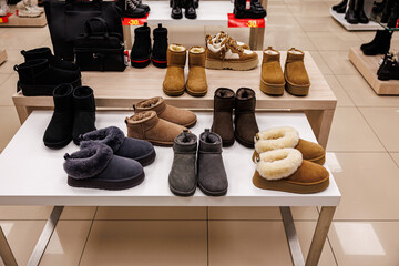 A variety of suede winter slippers and ankle boots in earthy shades with plush lining are neatly arranged on a store display. No visible logos or trademarks © ugis
