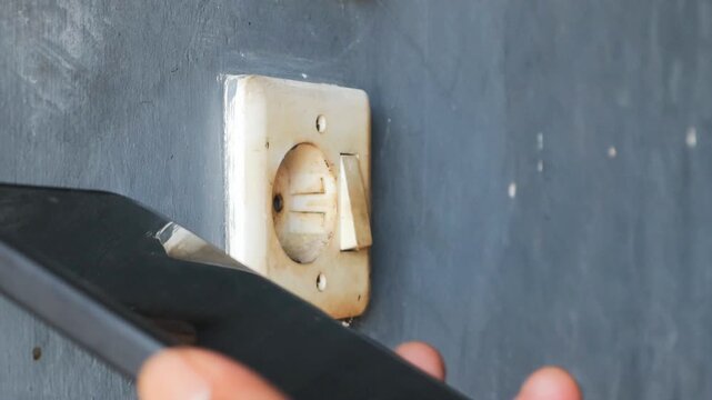 Man's hand unplugging a mobile phone charger from wall socket, promoting energy conservation and electrical safety practices in residential setting. 