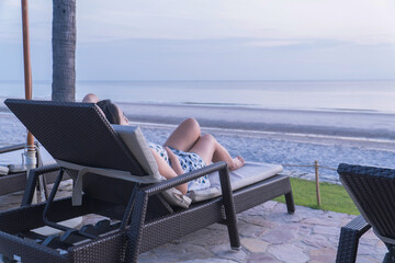 Asian woman relaxing on beach chair enjoying beautiful seaside view during summer vacation