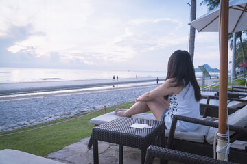 Asian woman relaxing on beach chair enjoying beautiful seaside view during summer vacation