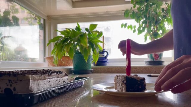 Servir tarta y encender vela en fiesta de cumplea&ntilde;os sobre encimera de cocina de casa