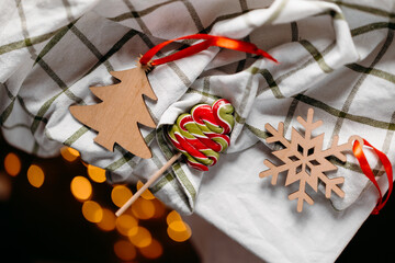 Christmas ornaments and candy on cozy textile with soft bokeh lights. Handmade holiday decor and warm festive atmosphere.