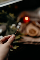 Hand holding sparkler in cozy winter setting with soft light. Intimate festive moment and warm Christmas mood.