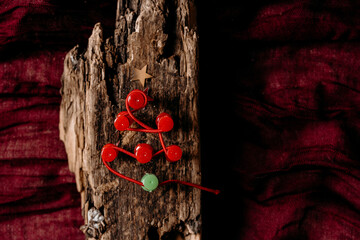 Rustic Christmas tree made from pins and branch on dark textile background. Natural winter decor and folk holiday concept.