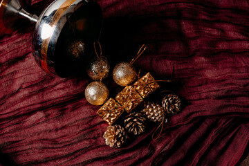 Christmas tree concept made from vintage ornaments spilling from glass on dark red textile. Dramatic festive still life.