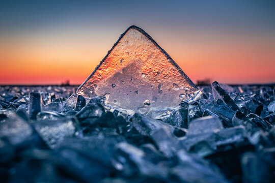 Fonyod, Hungary - Transparent ice cube on the frozen Lake Balaton on a cold winter afternoon with golden sunset lights