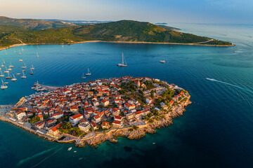 Primosten, Croatia - Aerial view of Primosten peninsula and old town on a sunny summer morning in Dalmatia, Croatia. Yachts, blue sky at sunrise on the Adriatic sea coast © zgphotography