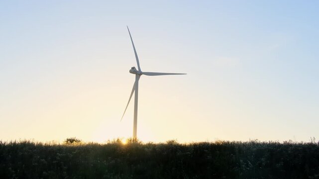 Wind turbine propeller rotates under clear sunset sky slow motion. Modern windmill works generating clean power at countryside slow motion