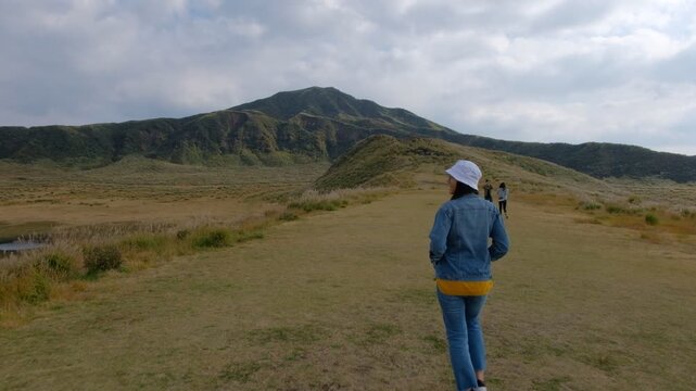 Woman standing in the green lanscape with mountain Aso background, Kusasenri, Aso, Kumamoto, Kyushu, Japan