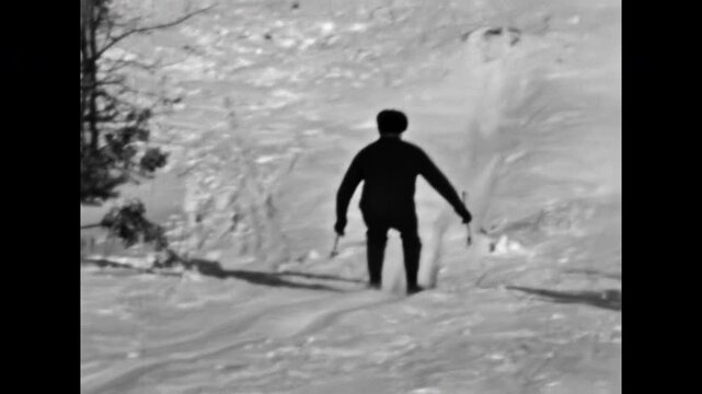 Man skiing down snowy slope, falling, back view. Skier jump off ramp falling in snow. Funny moment of winter sport. Hilarious adventure in ski resort. Old film. Archival retro 1960s. Vintage archive