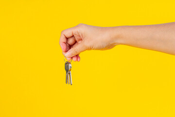 Key with a ring in hand on a yellow background.