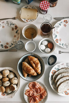 Breakfast table with croissants, eggs, bread, cheese, and jam