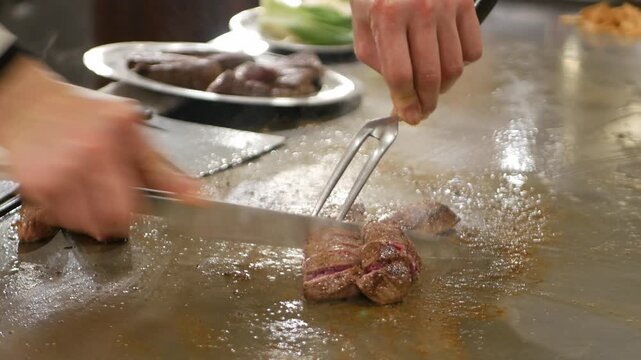 POV to kobe sirloin wagyu steak while cooking on teppan yaki flat pan in japanese style restaurant for lunch time. Chef cooking wagyu kobe beef sirloin steak on teppanyaki flat pan