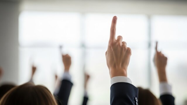 Group of people raising hands to ask question or vote. Audience participation in conference or seminar. Business meeting for discussion.