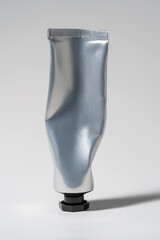 Minimalist silver aluminum cosmetic squeeze tube packaging with a black cap.