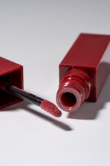 Rich red liquid lipstick with soft applicator and cap isolated on white background.