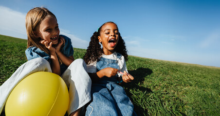 Cheerful girls enjoy outdoor play together on grass