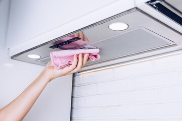 A Person Cleaning a Kitchen Range Hood with a Pink Cloth, Highlighting Home Care and Maintenance in a Modern Kitchen Setting